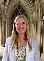 Student Kate Daniel wearing white coat standing under archway