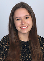 Headshot of Melissa Marchese smiling at camera with brown hair in front of shoulder wearing black speckled shirt in front of white backdrop