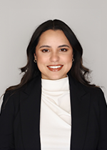 Headshot of student smiling at camera with dark brown curled hair wearing black blazer over white turtle neck