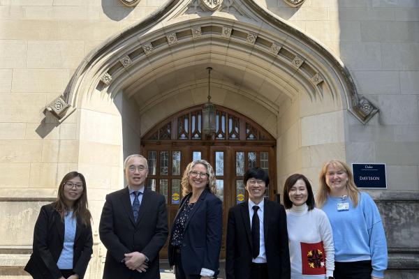 Group of six people standing in front of a building entrance