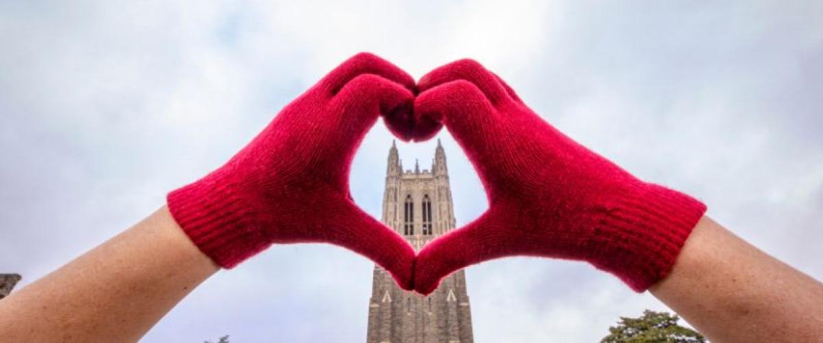 A hand in a heart shape in front of the Duke Chapel