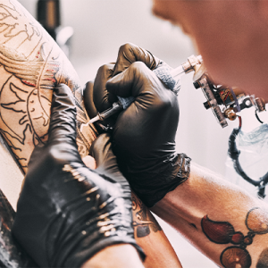 tattoo artist tattooing an arm. 